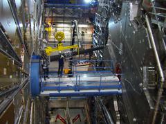 Zwei Physiker bauen das schwarze Stahlrohr mit dem LUCID-Detektor in den ATLAS-Detektor ein